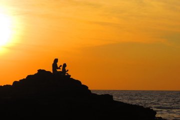 Two people sit on the coast of Goa, India.