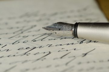 A fountain pen laying atop a written page.