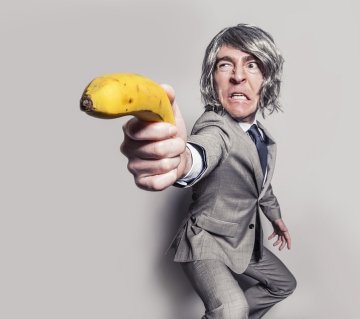 An anxious man holds a banana.